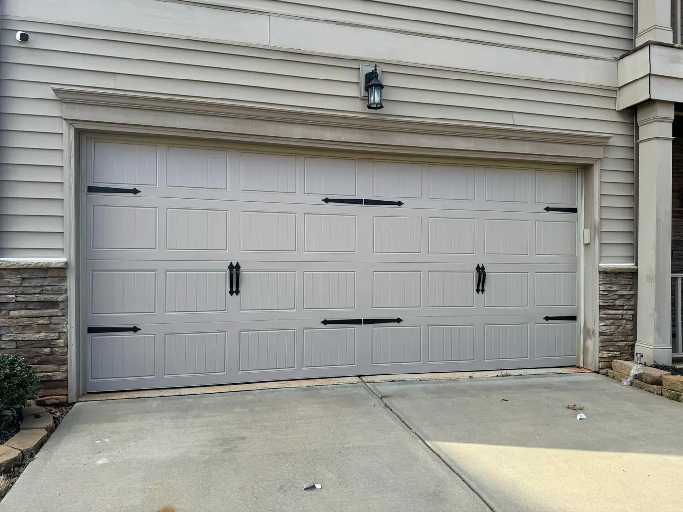 Tan carriage garage door with black decorative hardware