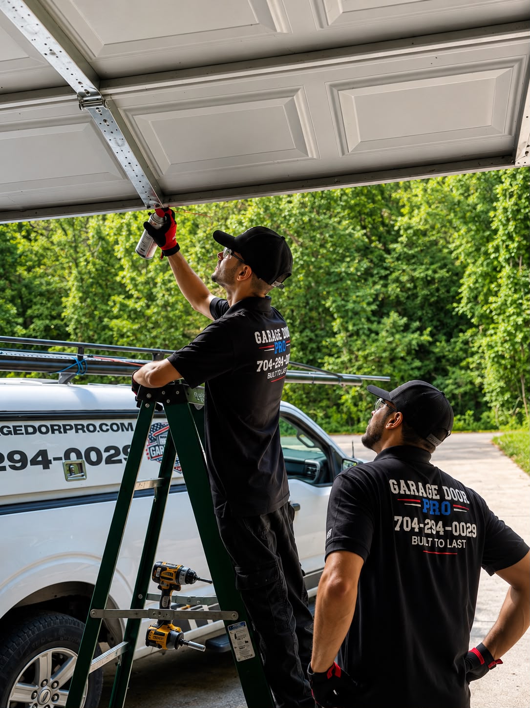 Garage Door Pro technicians performing garage door maintenance service - lubricating tracks and hardware - Charlotte NC 704-294-0029